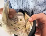 Ręce wkładają banknoty 200 zł do portfela. To może być nagroda jubileuszowa za długoletnią pracę.